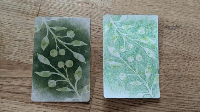 Photo of the back of an official Wingspan bonus card next to a homemade replica. Both have green botanical designs