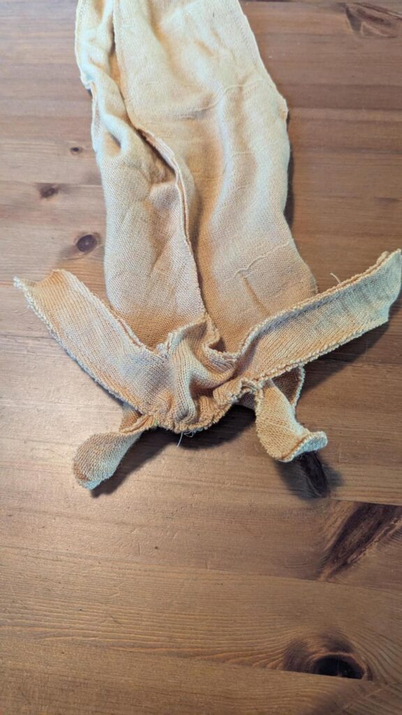 Photo of an inside-out slug sewing project with all the raw seams visible. The face has two longer tentacles sticking up like antennae and two smaller tentacles poking down like mouth parts. The body wiggles limply into the background