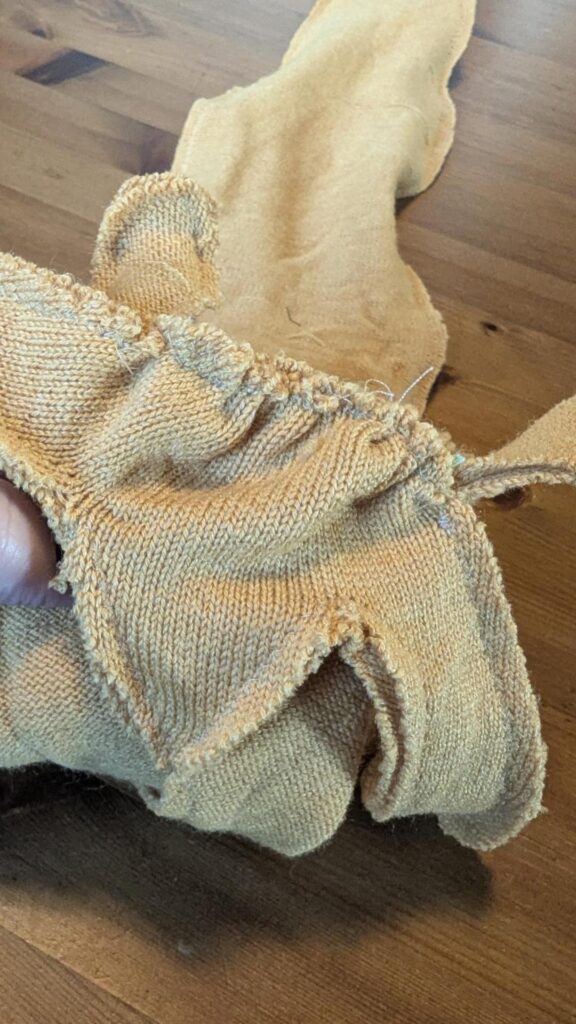 Close photo of a sewing project made from a medium weight woolly knit fabric. One seam is gathered. Various tentacles hang limply